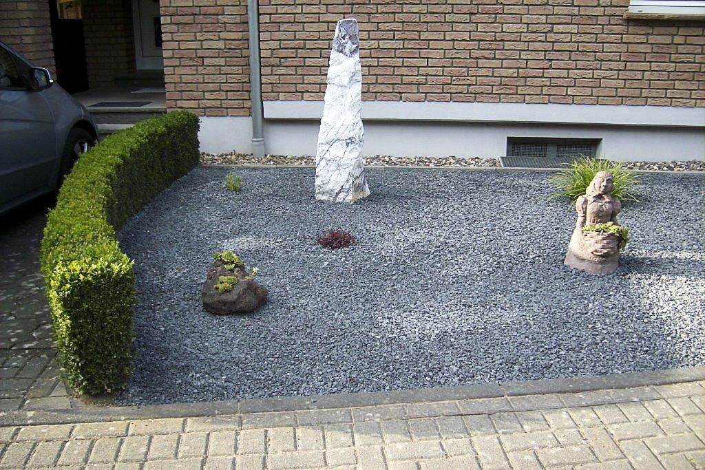 Vorgarten mit Kiesfläche, Formschnitthecke und Steinstele